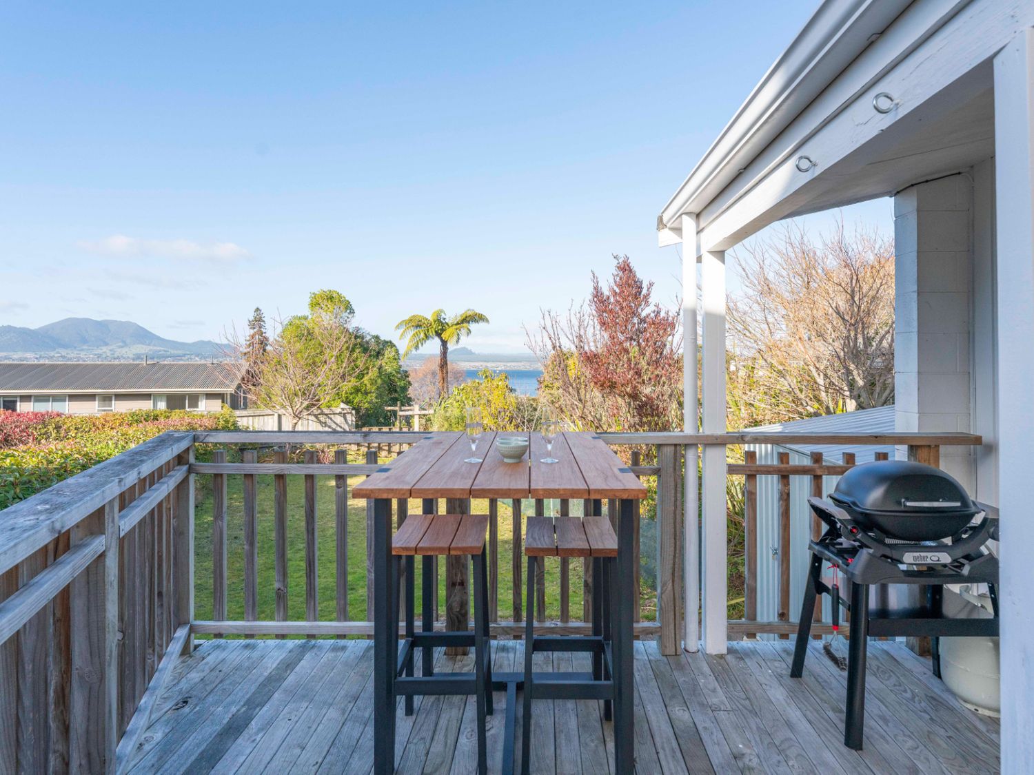 An outdoor deck with a table and chairs at The Cozy Corner - Taupo Holiday Home Acacia Bay