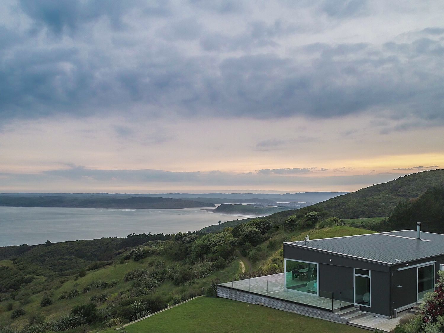 A house with a deck overlooking the ocean at The Glass House - Raglan Escape in Raglan