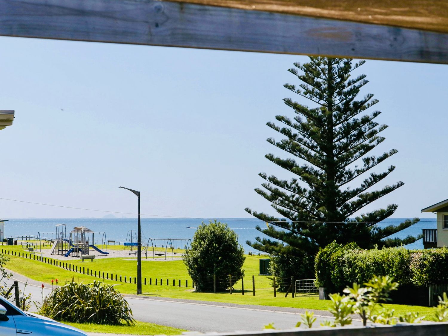 A view of a playground and sea at Whiritoa Holiday House in Whiritoa