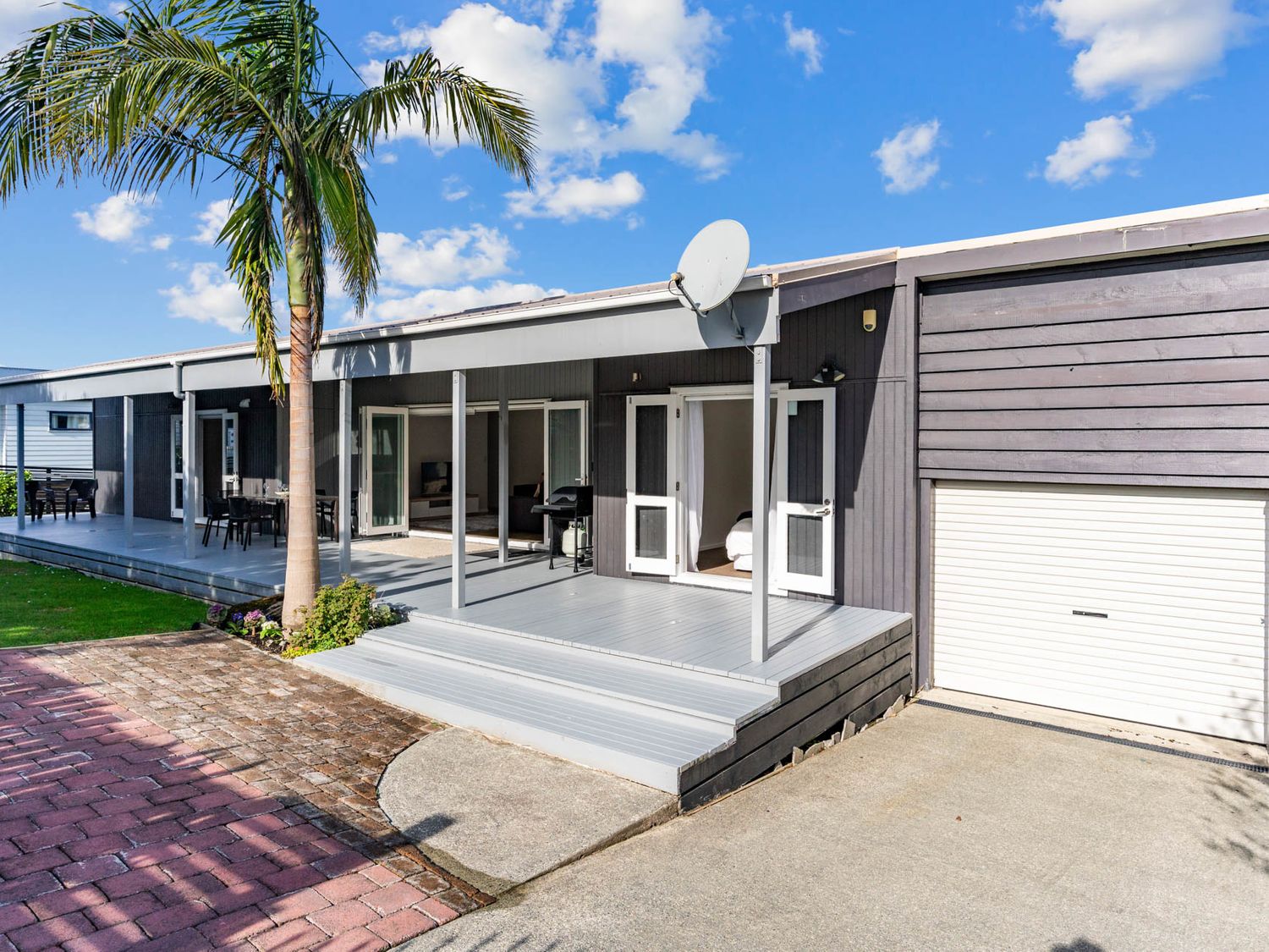 An outdoor area with seating and palm tree at Mangawhai Heads Holiday Home Mangawhai Heads
