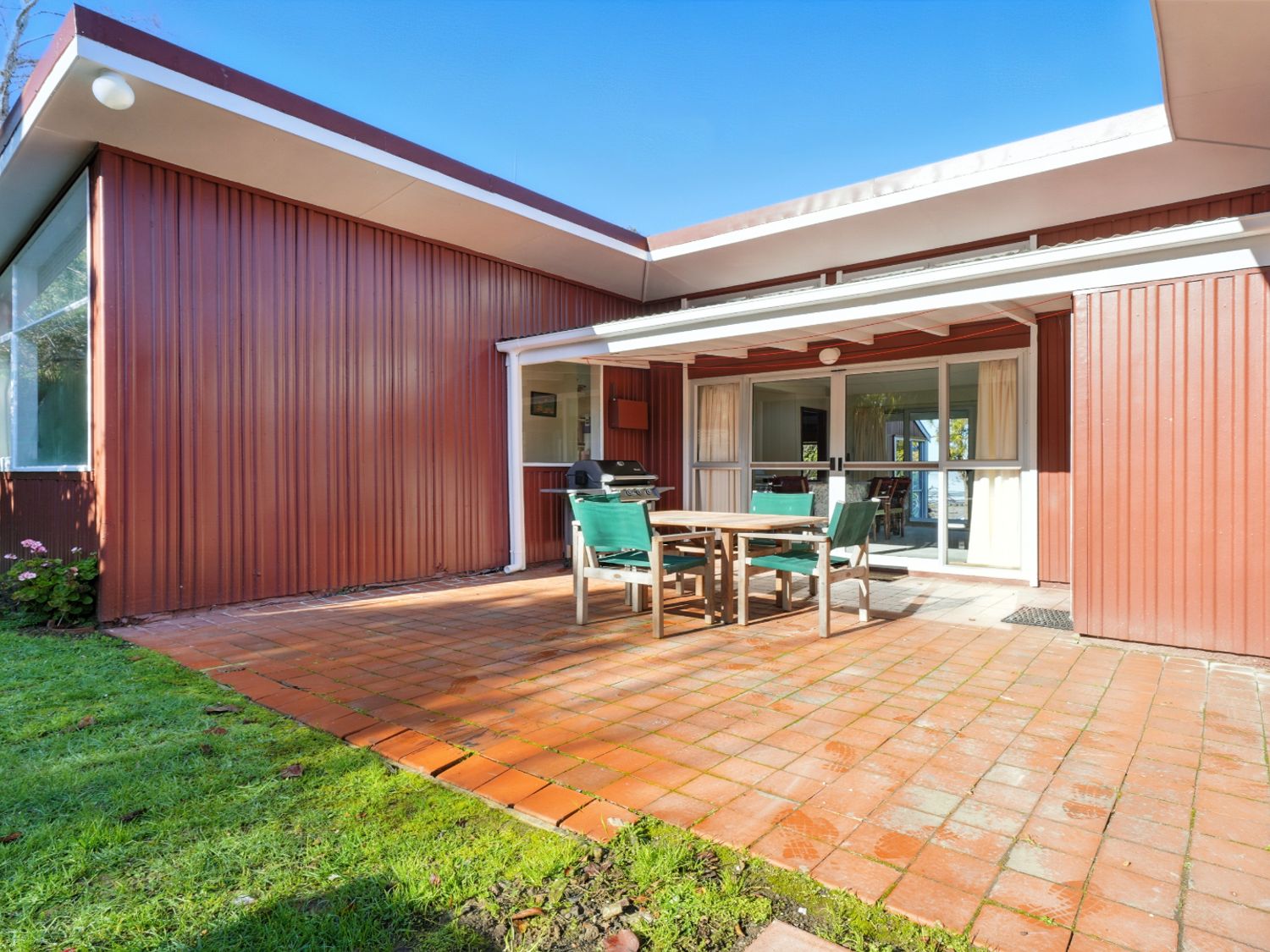 An outdoor patio with a table and chairs at Maison Pierre Rouge - Duvauchelle Holiday Home, Akaroa