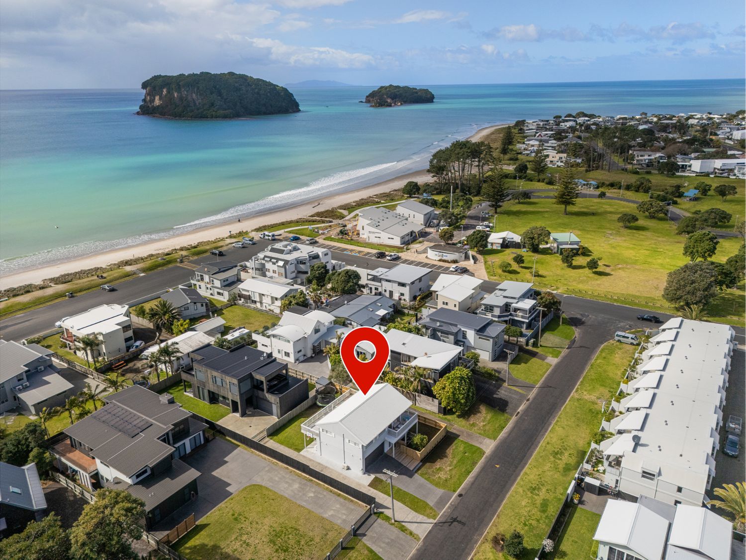 An aerial view of a beachside neighborhood with houses and a beach at a coastal location