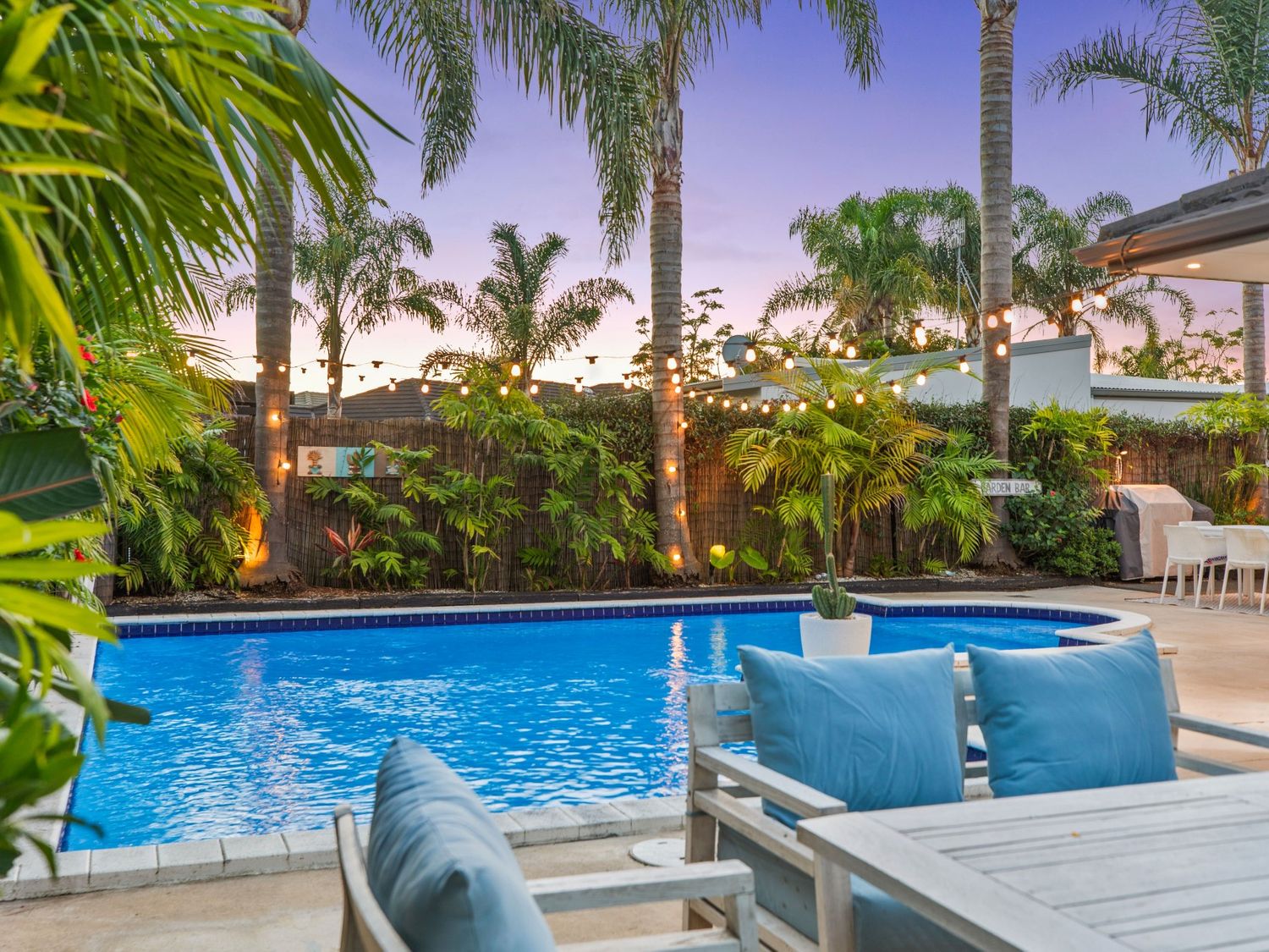 A swimming pool with outdoor furniture and palm trees at JB's Sanctuary - Papamoa Holiday Home Papamoa
