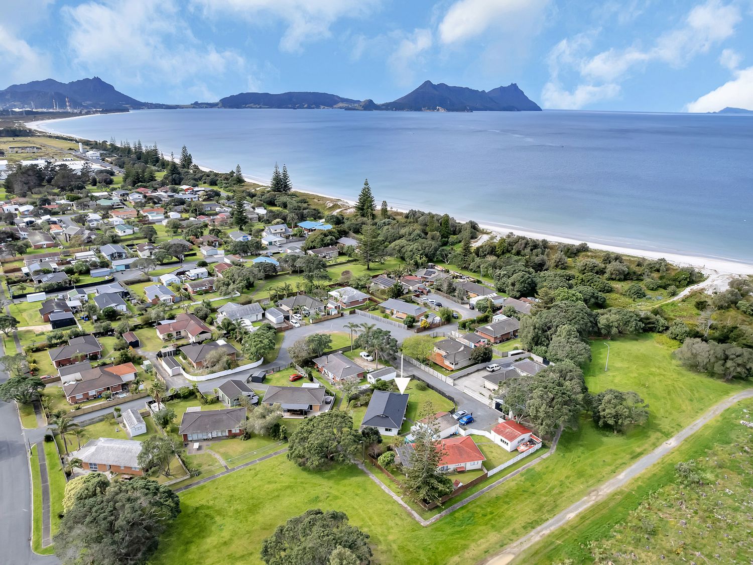 An aerial view of residential area with beach and mountains at Ruakaka Coastal Reserve Retreat in Ruakaka
