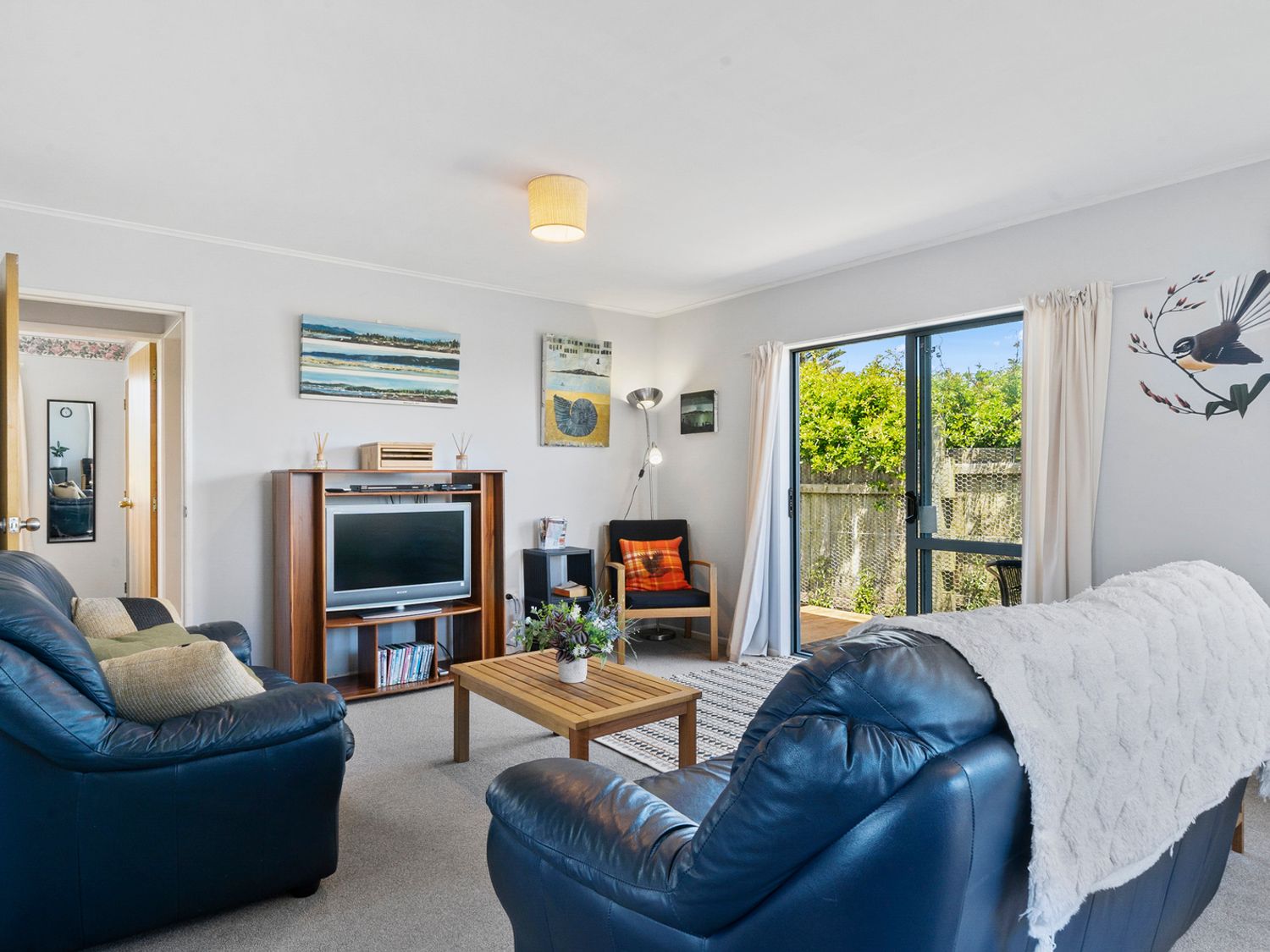 A living room with a sofa and television at Kapiti Breeze - Waikanae Beach Holiday Home