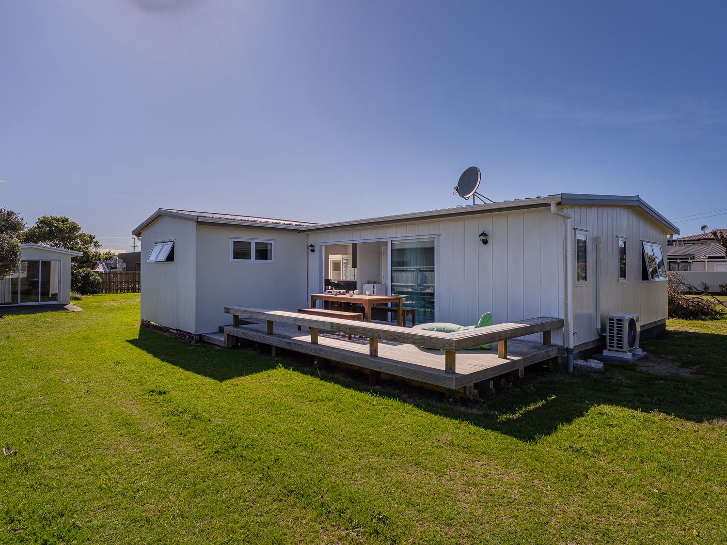 A house with a deck and table at Whangamata