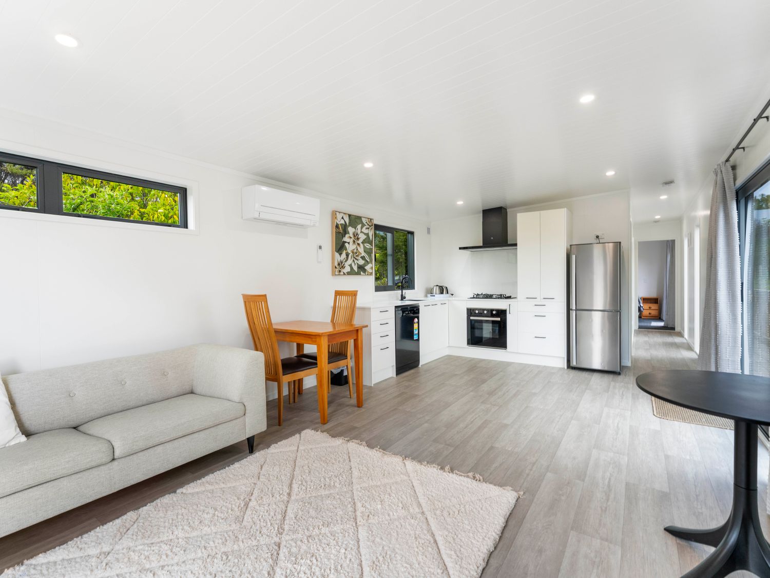 A living room with a couch, table and kitchen at Lake Taupo Holiday Home in Motuoapa
