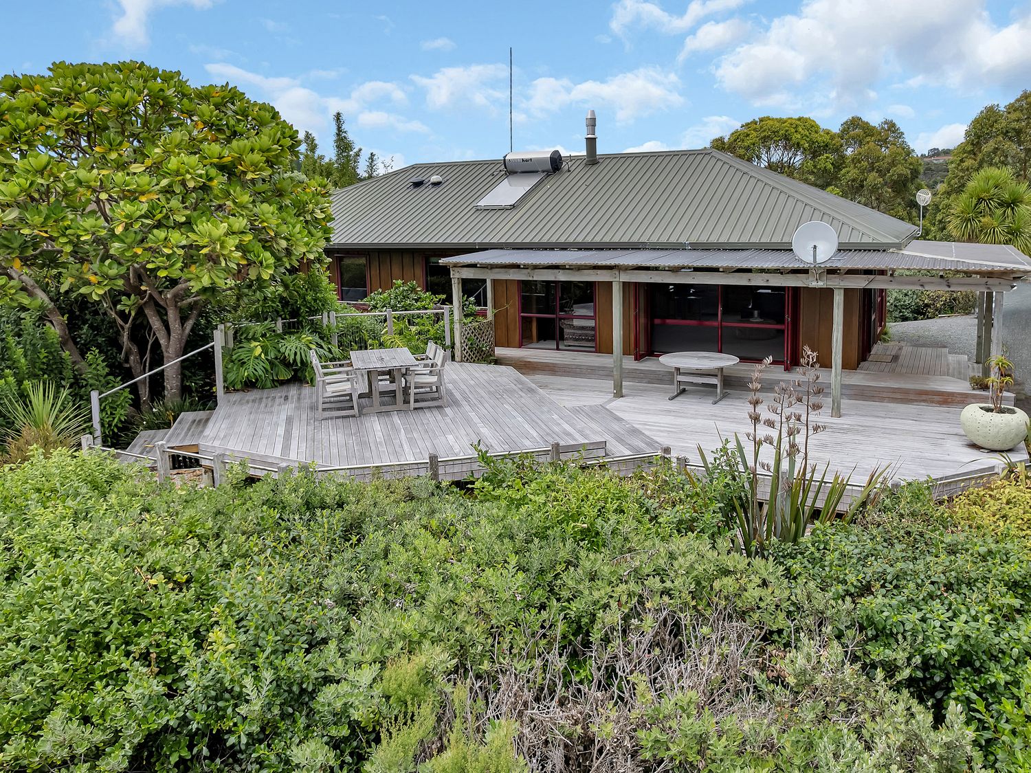 A house with a deck and dining area at Matapouri Holiday Home in Whangarei