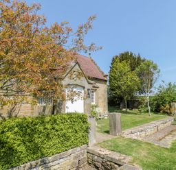 Exterior of a stone building with a red tiled roof surrounded by green bushes and trees at Fenwick Retreat at Fenwick Lodge Fenwick near Ponteland