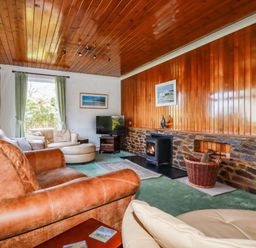 A living room with leather and fabric sofas a television fireplace and wood paneling at Trevow in Camborne
