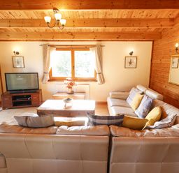 A living room with leather sofas cushions a wooden coffee table television and window at Jemima Lodge in Tattershall