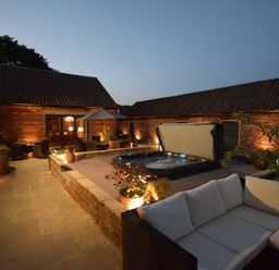 An outdoor patio area with a hot tub seating and plants at Sykes Lodge in Malton