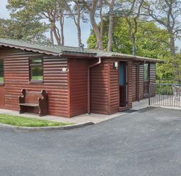 A wooden lodge with a bench outside at Daffodil Lodge in Saltburn-by-the-Sea