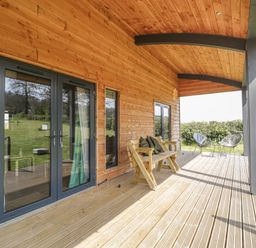 A wooden porch with a bench and two chairs with a small table on a grassy landscape at Foxglove in Sticklinch West Pennard Glastonbury