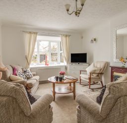 A living room with beige sofas armchairs a wooden coffee table television and window at Casa Carmen Weymouth