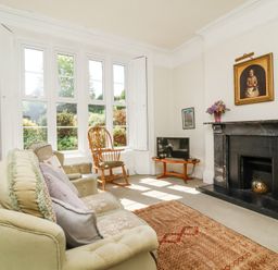 A living room with sofa armchair rocking chair fireplace and TV at The Old Vicarage in Tiverton