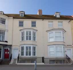 A row of cream-colored townhouses with bay windows and white doors at Low Tide in Weymouth
