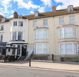 A street view of terraced buildings with a restaurant and residential entrances at Low Tide in Weymouth