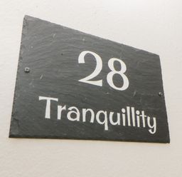 Black house number sign with white text 28 Tranquillity on a light wall at Tranquillity Rosecraddoc Lodge near Liskeard