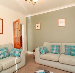 A living room with two sofas with blue plaid cushions and framed pictures on the walls at Brewers House in Weymouth