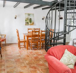 A dining area with a wooden table and chairs near a black spiral staircase and seating at An Teach Ban in Rossaveel County Galway