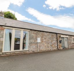 A stone cottage with large windows and a grey roof under a blue sky at Hemmel Cottage in Chatton