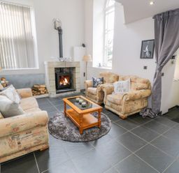 A living room with a fireplace sofas coffee table and a curtain at Horeb Chapel House in Tanygrisiau