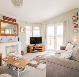 A living room with two sofas a coffee table a TV on a stand and decor at Lake View Lodge in Marston near Barkston
