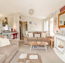 A living room with two beige sofas a wooden coffee table and a fireplace at Lake View Lodge in Marston near Barkston