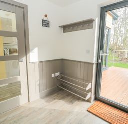 A corner of a room with a door leading outside and a wall-mounted coat rack at Lambs Lodge in Bamburgh