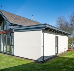A modern house with large glass windows and patio furniture on a deck at Lambs Lodge in Bamburgh