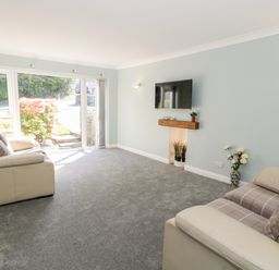 A living room with two sofas a wall-mounted TV and a window looking outside at Clyd Fan in Harlech