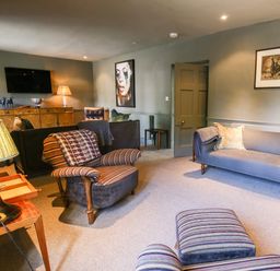 A living room with striped armchairs a gray sofa and wooden furniture at The Old Post Office in Coln St Aldwyns