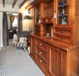 A dining room with a wooden dresser chair and a floor lamp at Victoria Cottage in Amble