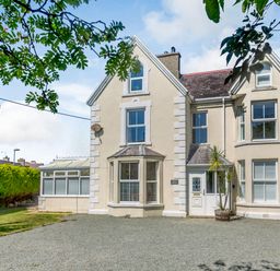 A residential building with bay windows and a gravel driveway at Bryn Rhosyn in Nefyn
