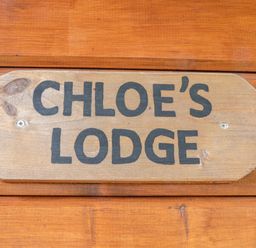 A wooden sign with Chloe's Lodge written on it mounted on wooden wall at Chloe's Lodge in Middleton Ryedale