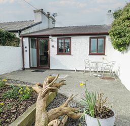 An outdoor area with a house and table with chairs at Bwthyn in Moelfre