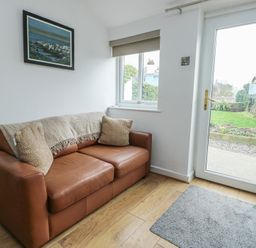 A snug with a sofa and a door leading outside at Bwthyn in Moelfre