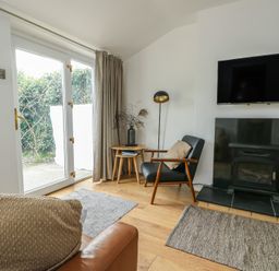 A living room with a fireplace and television at Bwthyn in Moelfre