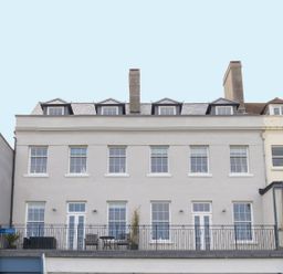A four-story building with multiple windows and a balcony with outdoor furniture at 6 The Beaches in Weymouth