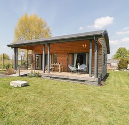 A wooden cabin with a covered porch and outdoor table and chairs in a grassy area at Primrose in Sticklinch West Pennard Glastonbury