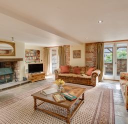 A living room with sofas around a coffee table and a fireplace at Manor Farm Barn in Dewlish