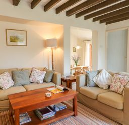 A living room with two beige sofas wooden coffee table and a floor lamp at Woodstock Cottage in Birchill near Chardstock