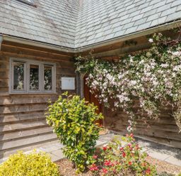 Exterior corner of a wooden house with a window a mailbox flowering vines and garden shrubs at Trevinny Lodge No 37 in Davidstow near Boscastle