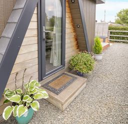 An outdoor gravel area with potted plants a glass door and wooden railings at Alstroemeria Bretforton near Evesham