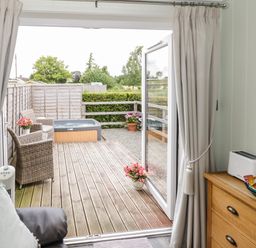 A patio with wicker chairs and a hot tub seen from inside a room with drawers and a toaster at Alstroemeria Bretforton near Evesham
