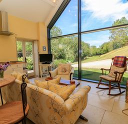 A living room with a large window and seating at Pheasant Cottage in Priston Village, BATH