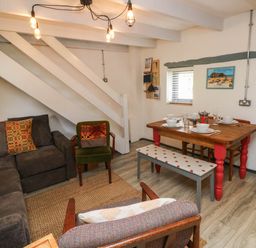 A living room with a dining area and staircase at Farmhand Cottage near Narberth