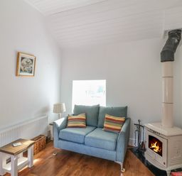 A living room with a blue sofa and wood burning stove at The Old White Cottage in Shillelagh County Wicklow