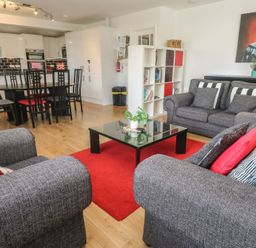 A living room with grey sofas and black dining table in an open plan kitchen at Tremar in Carbis Bay